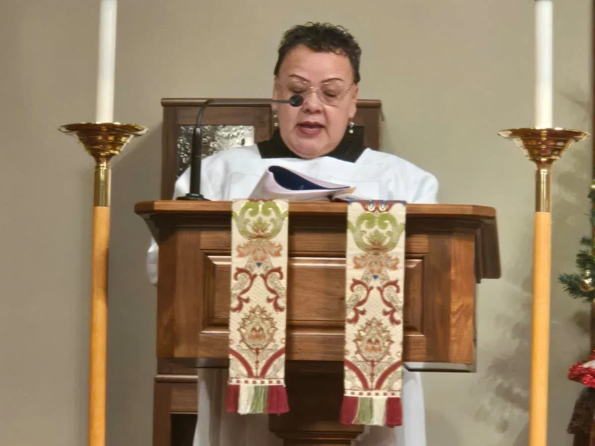 A lector reading from the lectern between two tall candles.