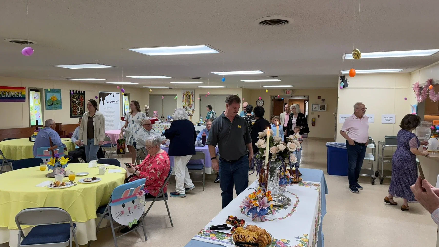 Parishioners talking over tables in the parish hall at coffee hour.