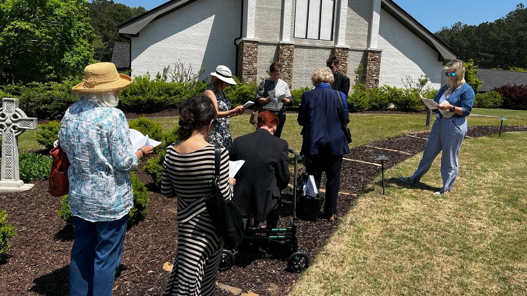 Parishioners walking the outdoor Stations of the Cross beside the church.